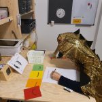 Kind im Drachenkostüm am Schreibtisch während der Autismus-Therapie
