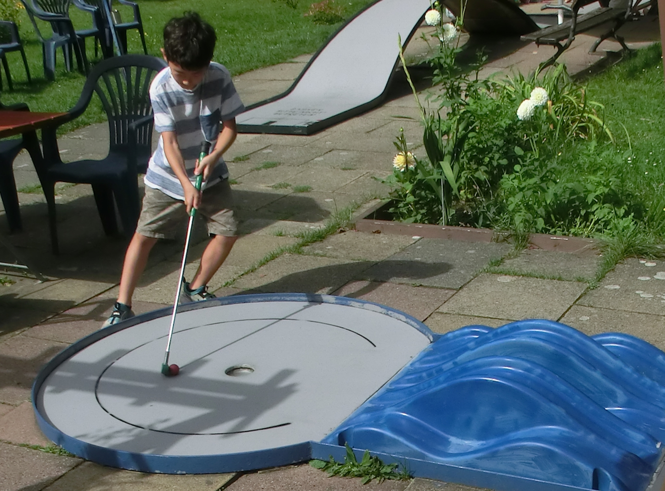 Junge spielt an einer Minigolfbahn mit blauem Hindernis