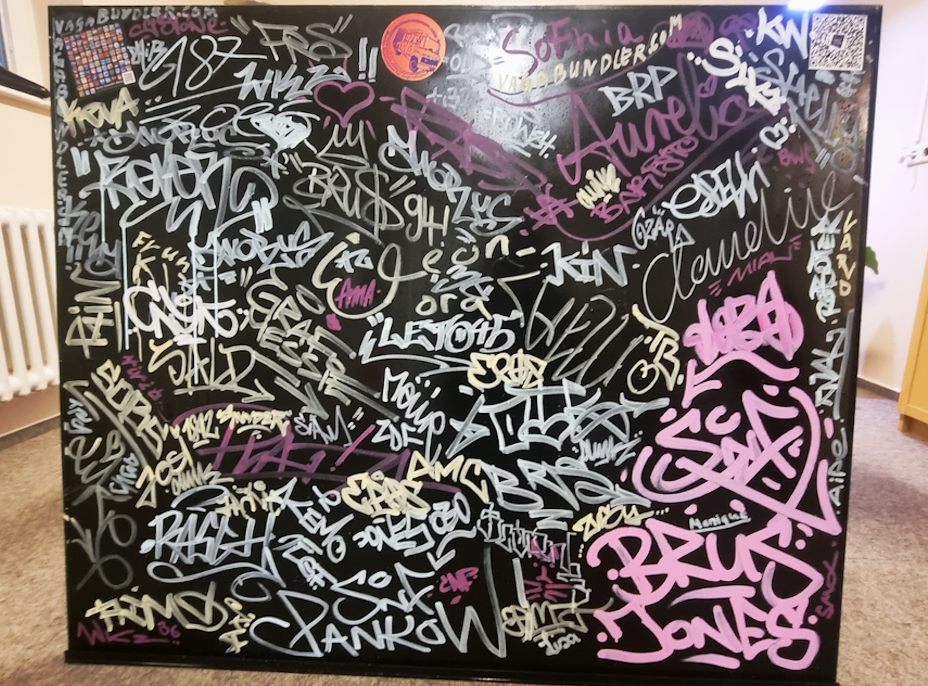 Schwarze Tafel mit unzähligen Tags (Unterschriften von Graffiti-Künstlern)