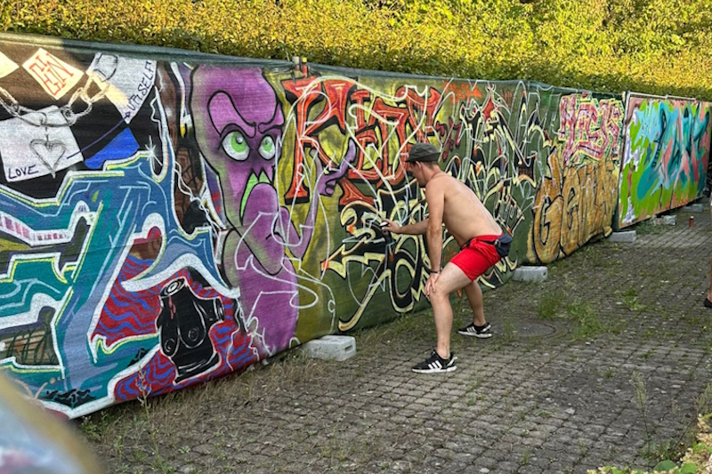 Junger Spryer arbeitet an Graffiti-Wand
